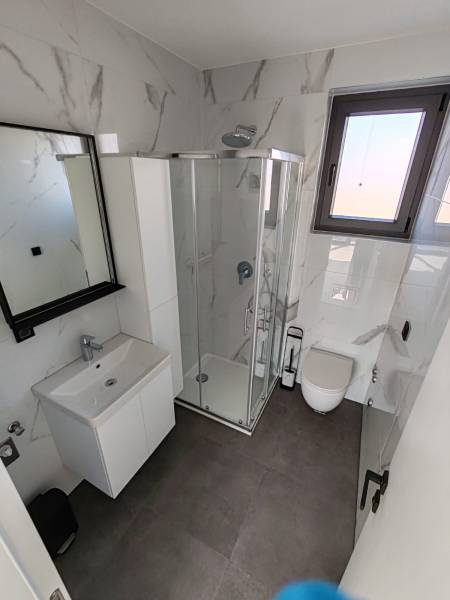 CHORVÁTSKO - Apartmány na ostrove VIR, Zadar - Kúpeľňa v 3-izbovom byte s bielym nábytkom a sprchovým kútom.