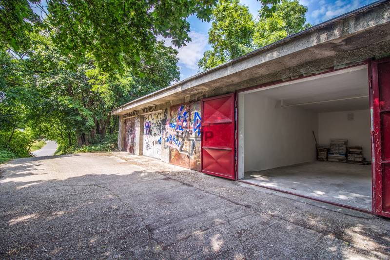 Pozrite si 17m², ZREKONŠTRUOVANÚ garáž, pri nemocnici Kramáre - Garáže s graffiti a otvorenými dverami na ulici Opavská obklopené zeleňou.