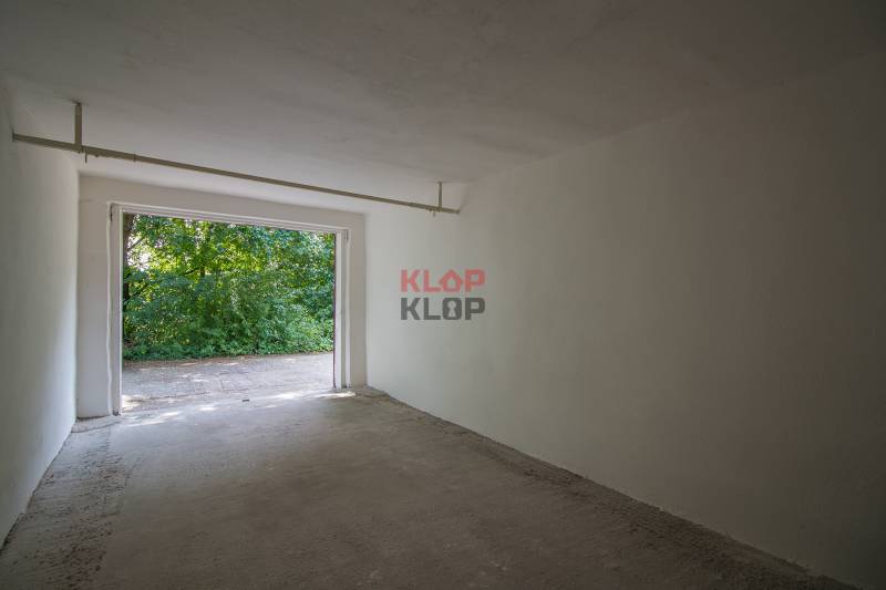 Pozrite si 17m², ZREKONŠTRUOVANÚ garáž, pri nemocnici Kramáre - Prázdna garáž na ulici Opavská, s výhľadom na zeleň a betónovou podlahou.