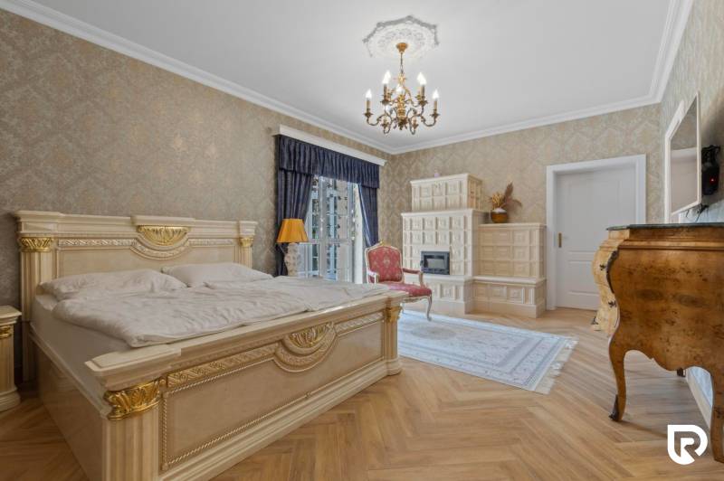 Exkluzívna honosná kúria | 3 ha pozemok | Dunakiliti - HU - Luxusná spálňa so zlatými detailmi, podlahou s dreveným dekorom a kachľovou pecou.