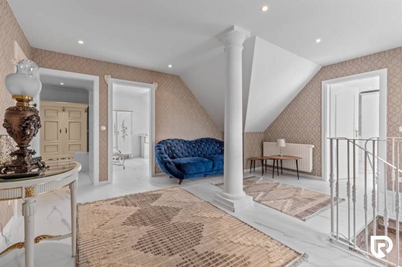 Exkluzívna honosná kúria | 3 ha pozemok | Dunakiliti - HU - Interiér so stĺpom, modrým gaučom a kobercami, Zvláštne nehnuteľnosti.