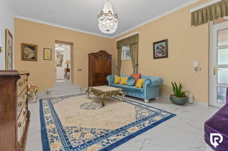 Exkluzívna honosná kúria | 3 ha pozemok | Dunakiliti - HU - Obývacia izba s modrou sedačkou, drevenými skrinkami a lustrom, Zvláštne nehnuteľnosti.