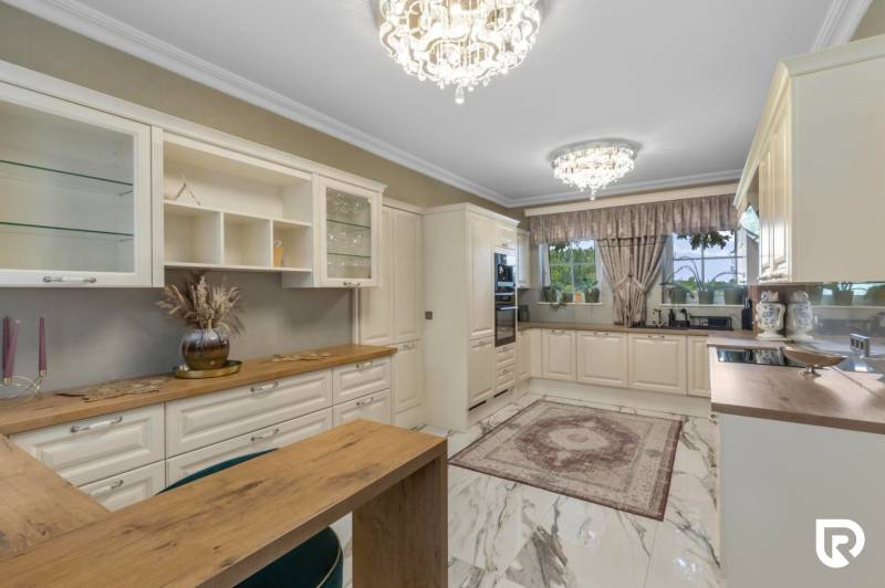 Exkluzívna honosná kúria | 3 ha pozemok | Dunakiliti - HU - Elegantná kuchyňa so svietidlami, drevenými dekoráciami a podlahou s dreveným dekorom.