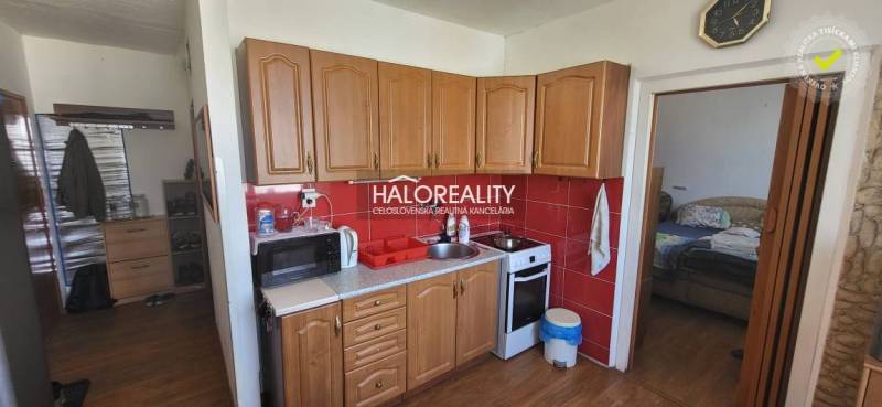 Predaj, jednoizbový byt Žiar nad Hronom, Novomeského - Kuchyňa v 1-izbovom byte s drevenými skrinkami, mikrovlnkou a sporákom.