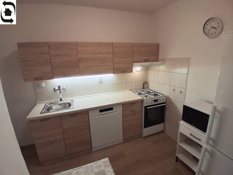 Prenájom 3 izbového bezbariérového bytu, Vetvová ulica, Bratislava - Kuchyňa v 3-izbovom byte s linkou, sporákom, umývačkou a podlahou s dreveným dekorom.