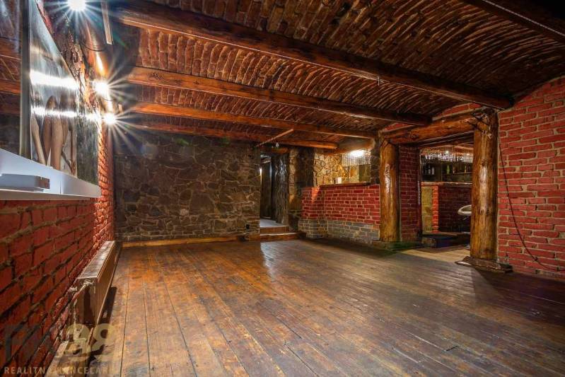 Exkluzívne: Predaj budovy v centre mesta Poprad - Interiér s podlahou s dreveným dekorom, tehlové a kamenné steny, strop s drevenými trámami.