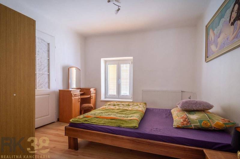 Exkluzívne: Predaj budovy v centre mesta Poprad - Spálňa s posteľou, zrkadlom a podlahou s dreveným dekorom.