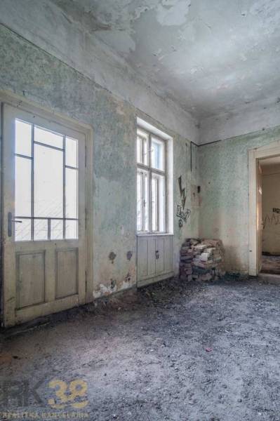 Exkluzívne: Predaj budovy v centre mesta Poprad - Interiér budovy s poškodenými stenami, dverami a oknami, tehly na podlahe.