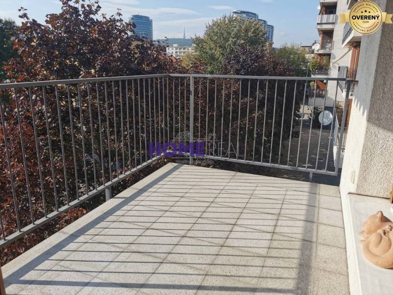 SLNEČNÝ KOMPLETNE ZARIADENÝ 2 IZB. BYT PRI ŠTRKOVECKOM JAZERE.  - Balkón 2-izbového bytu na Drieňovej ulici v Bratislave - Ružinove so zeleňou v pozadí.