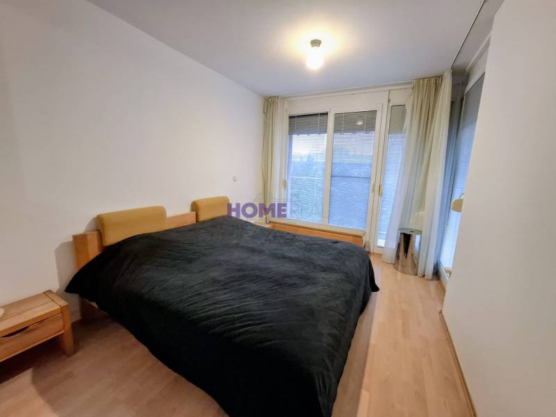 SLNEČNÝ KOMPLETNE ZARIADENÝ 2 IZB. BYT PRI ŠTRKOVECKOM JAZERE.  - Spálňa v 2-izbovom byte s podlahou s dreveným dekorom a veľkými oknami.