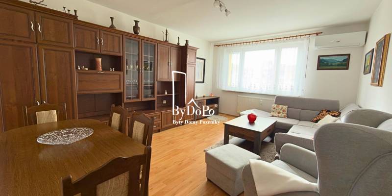 3-izbový zariadený byt, 78 m2, zasklenná loggia, Považská ul., Nitra - Obývacia izba v 3-izbovom byte s podlahou s dreveným dekorom a veľkou sedacou súpravou.