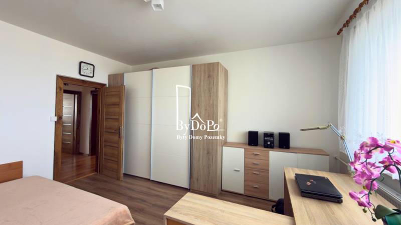 3-izbový zariadený byt, 78 m2, zasklenná loggia, Považská ul., Nitra - Spálňa s podlahou s dreveným dekorom, vstavaná skriňa a kvet v 3-izbovom byte.