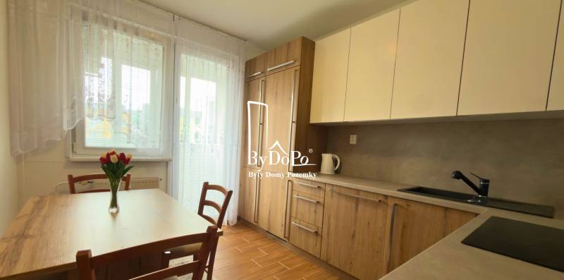 3-izbový zariadený byt, 78 m2, zasklenná loggia, Považská ul., Nitra - Kuchyňa v 3-izbovom byte s dreveným dekorom a svetlým nábytkom, elegantné kvety na stole.