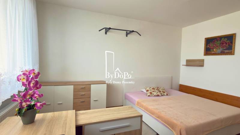 3-izbový zariadený byt, 78 m2, zasklenná loggia, Považská ul., Nitra - Spálňa s posteľou, skriňou a dekoratívnymi kvetmi v 3-izbovom byte.