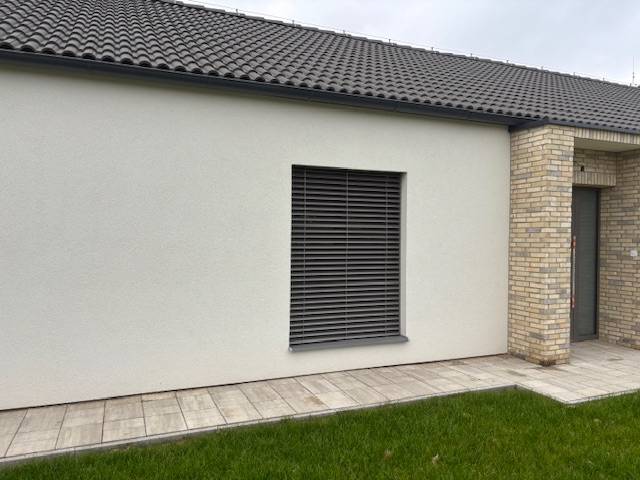 Na predaj dizajnový 4-izbový rodinný dom v Tomášove - Exteriér rodinného domu na Fialkovej v Tomášove s tehlovým obkladom a trávnikom.