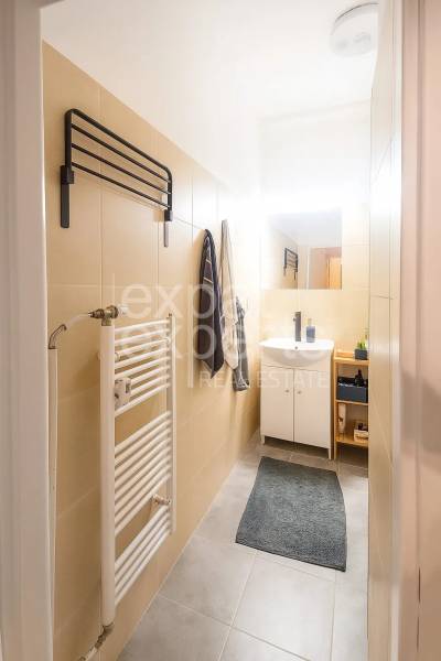 Svetlý, jedinečný 2i byt 62m2, po rekonštrukcií, s pivnicou   - Kúpeľňa v 3-izbovom byte so svetlými obkladačkami, umývadlom a rebríkovým radiátorom.