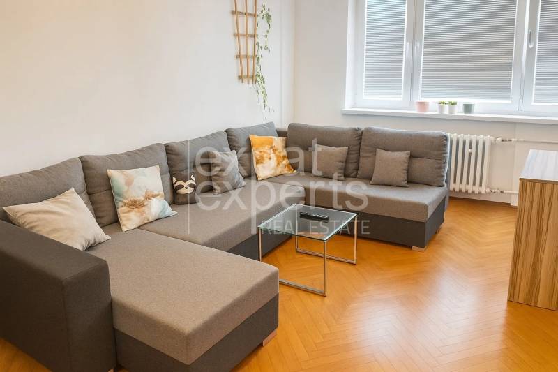 Svetlý, jedinečný 2i byt 62m2, po rekonštrukcií, s pivnicou   - Obývačka s pohodlnou sedačkou a podlahou s dreveným dekorom v 3-izbovom byte.