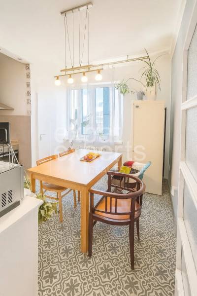 Svetlý, jedinečný 2i byt 62m2, po rekonštrukcií, s pivnicou   - Jedáleň v 3-izbovom byte s dreveným stolom, stoličkami a dekoratívnou podlahou.