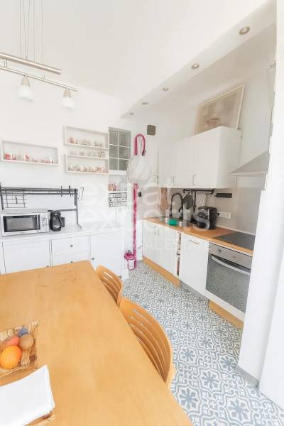 Svetlý, jedinečný 2i byt 62m2, po rekonštrukcií, s pivnicou   - Kuchyňa v 3-izbovom byte s jedálenským stolom, vzorovanou podlahou a bielymi skrinkami.