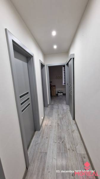 Nový rodinný dom, 7 minút od centra Košíc v tichej uličke pod lesom - Chodba v rodinnom dome s podlahou s dreveným dekorom a sivými dverami.