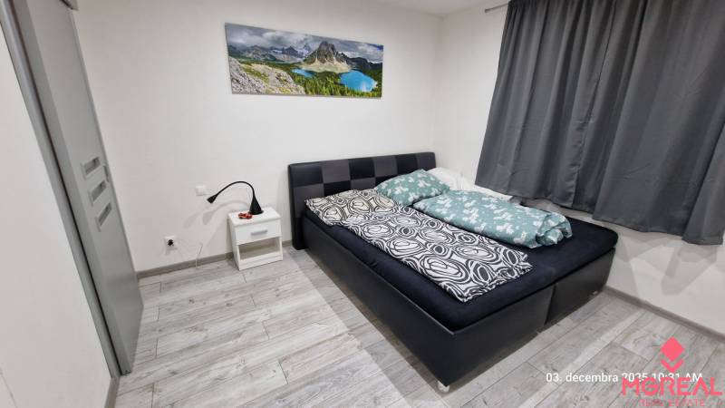 Nový rodinný dom, 7 minút od centra Košíc v tichej uličke pod lesom - Spálňa v rodinnom dome s posteľou, nočným stolíkom a podlahou s dreveným dekorom.