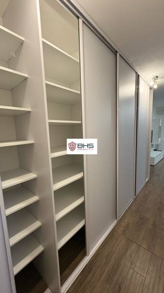 Predaj 1ibyt (garsonka) v uzavretom areáli v DNV (novostavba) - Vstavaná skriňa v 1-izbovom byte s posuvnými dverami a podlahou s dreveným dekorom.