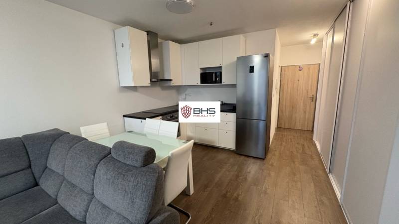 Predaj 1ibyt (garsonka) v uzavretom areáli v DNV (novostavba) - Obývacia izba s kuchyňou, sedačkou a podlahou s dreveným dekorom v 1-izbovom byte.