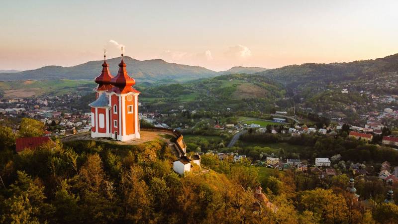 Banská Štiavnica – Investičné pozemky pri rodinných domoch - Kalvária na kopci s panorámou Banskej Štiavnice, obklopená poľnohospodárskymi a lesnými pozemkami.