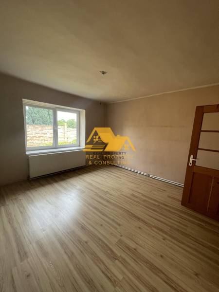 Exkluzívne! Predám rodinný dom v obci Svodín - Izba s veľkým oknom a podlahou s dreveným dekorom v rodinnom dome.