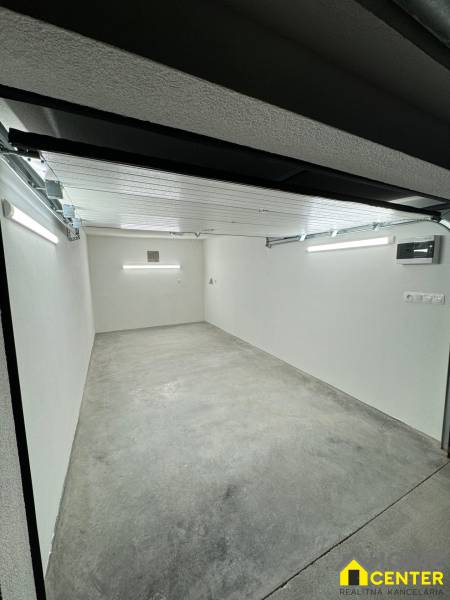 PREDAJ zrekonštruovaná garáž na ulici Slnečná - KOMÁRNO - Priestranný interiér garáže s betónovou podlahou a bielymi stenami.