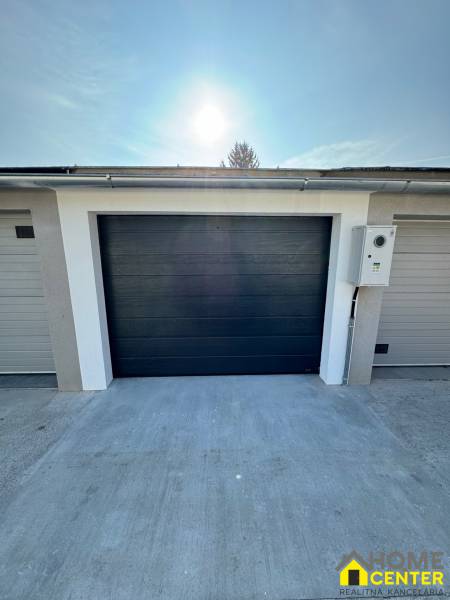 PREDAJ zrekonštruovaná garáž na ulici Slnečná - KOMÁRNO - Garáže na Slnečnej ulici v Komárne s tmavými bránami a betónovou plochou.
