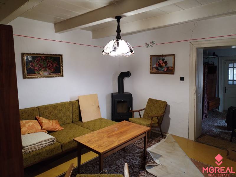 Na predaj vidiecky rodinný dom v obci Dolný Pial - Obývacia izba rodinného domu s kachľami, starožitným nábytkom a dekoráciami.