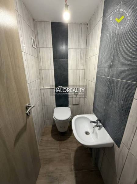 Predaj, rodinný dom Chynorany - Toaleta s umývadlom v rodinnom dome, obkladaná steny, podlaha s dreveným dekorom.