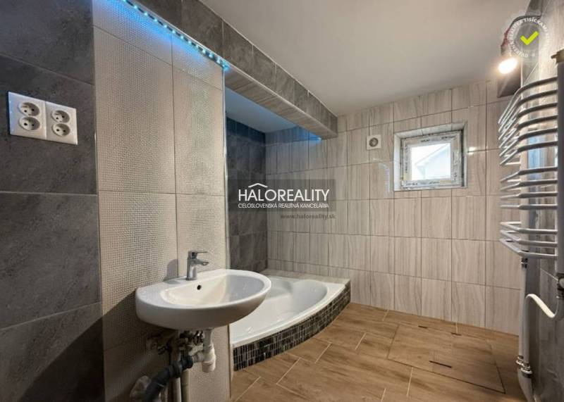 Predaj, rodinný dom Chynorany - Kúpeľňa rodinného domu s vaňou, umývadlom a podlahou s dreveným dekorom.