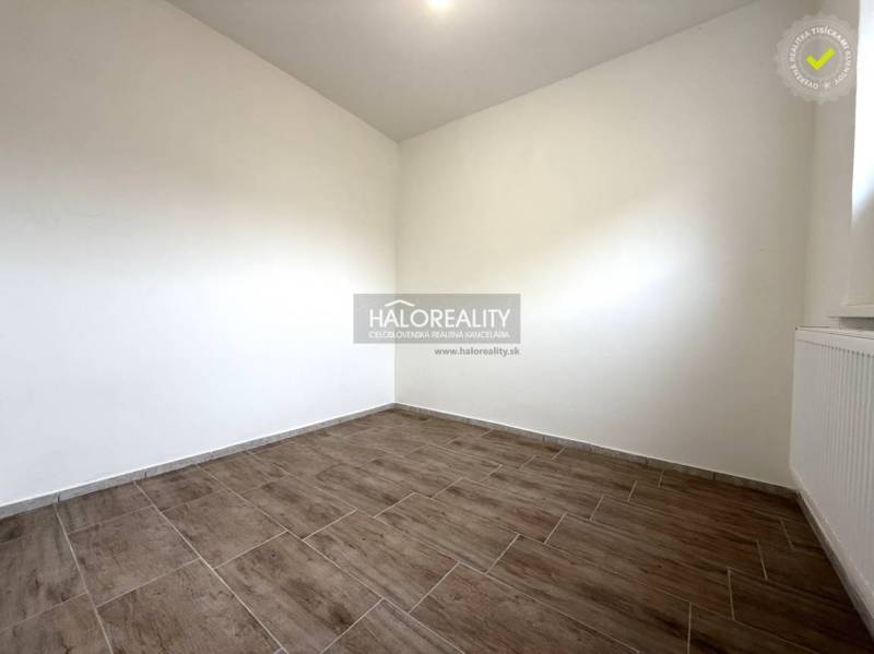 Predaj, rodinný dom Chynorany - Izba s podlahou s dreveným dekorom v rodinnom dome, svetlé steny, radiátor.