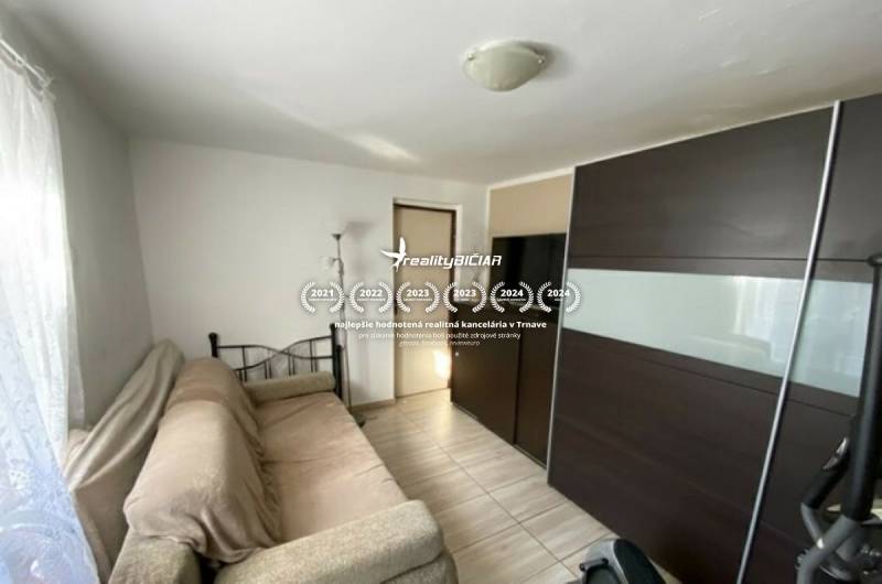 V exkluzívnom zastúpení majiteľa ponúkame na predaj rodinný dom - Obývacia izba v rodinnom dome s gaučom, veľkou skriňou a podlahou s dreveným dekorom.