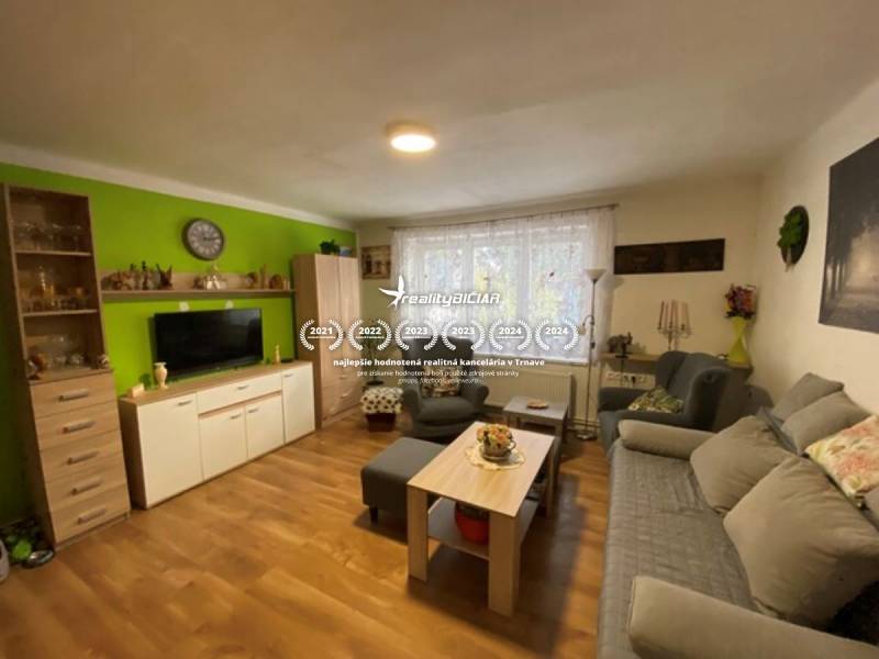 V exkluzívnom zastúpení majiteľa ponúkame na predaj rodinný dom - Obývacia izba v rodinnom dome s podlahou s dreveným dekorom, pohodlnými sedačkami a dekoráciami.