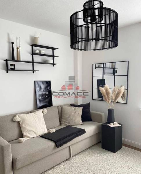 Exkl.4 iz novostavba RD - tepelné čerpadlo - Moravany nad Váhom - Obývačka v rodinnom dome s pohodlnou sedačkou, dekoratívnymi poličkami a moderným lustrom.