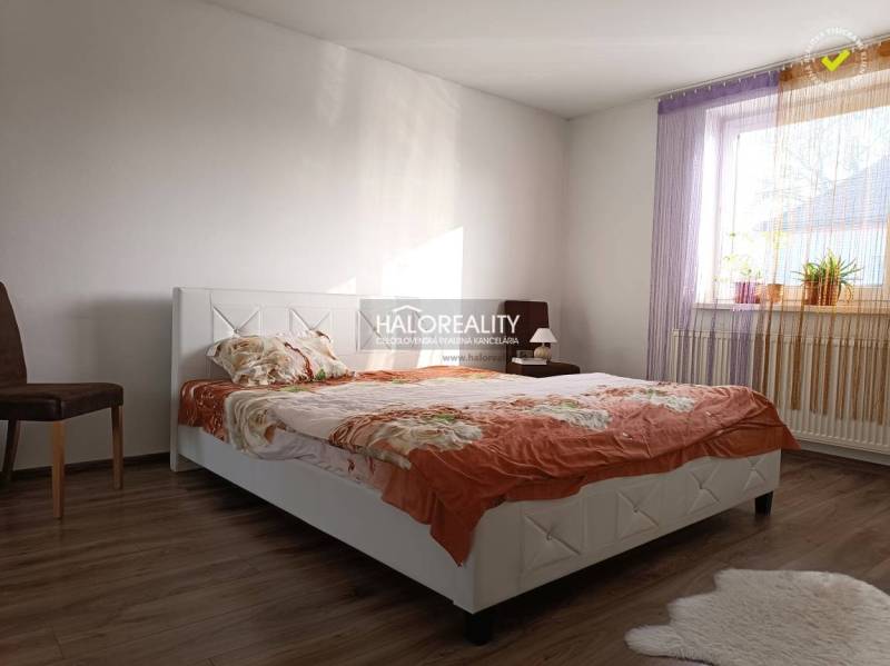 Predaj, rodinný dom Trebišov, NOVÁ SKVELÁ CENA ul. J... - Spálňa obsahuje posteľ so vzorovaným prehozom, drevenú podlahu a okno s rastlinami.