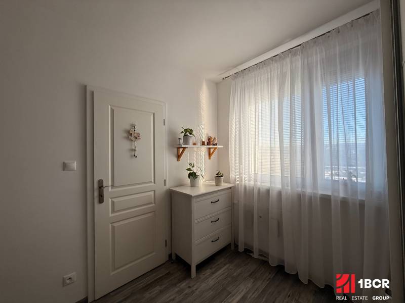 KRÁSNY, ÚTULNÝ A ŠTÝLOVÝ 3 IZBOVÝ BYT | DUBRAVKA - Svetlá izba v 3-izbovom byte s komodou, závesmi a rastlinami vo vnútri.