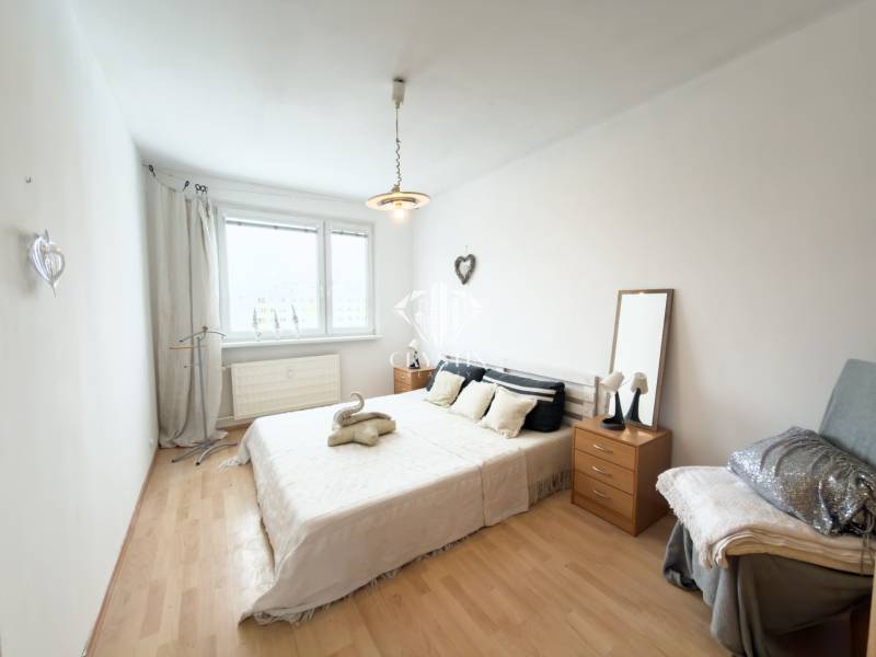 Na predaj 2,5- izbový byt Žilina-Solinky - Svetlá spálňa s posteľou a podlahou s dreveným dekorom v 2-izbovom byte.