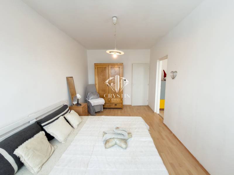 Na predaj 2,5- izbový byt Žilina-Solinky - Spálňa s posteľou, skriňou a podlahou s dreveným dekorom v 2-izbovom byte.