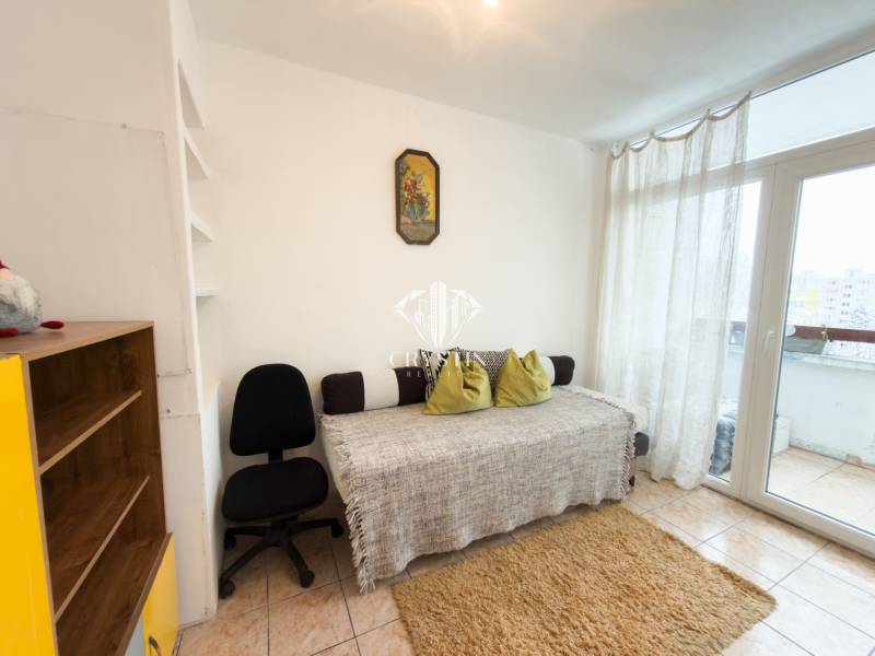 Na predaj 2,5- izbový byt Žilina-Solinky - Obývacia izba v 2-izbovom byte s pohovkou, koberec, stolička, regál na knihy.