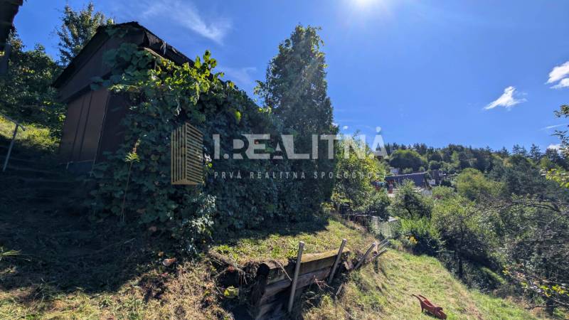 ZÁHRADA S UNIMOBUNKOU A VÝHĽADOM NA ZVOLEN , 465M2, ZVOLEN – HÁJIK - Záhrady na Hájiku vo Zvolene, vidno chatku obklopenú vegetáciou a slnečné počasie.