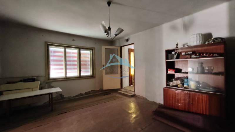 Rodinný dom v obci Čebovce v okrese Veľký Krtíš. - Izba v rodinnom dome s jednoduchým nábytkom a lampou na strope.