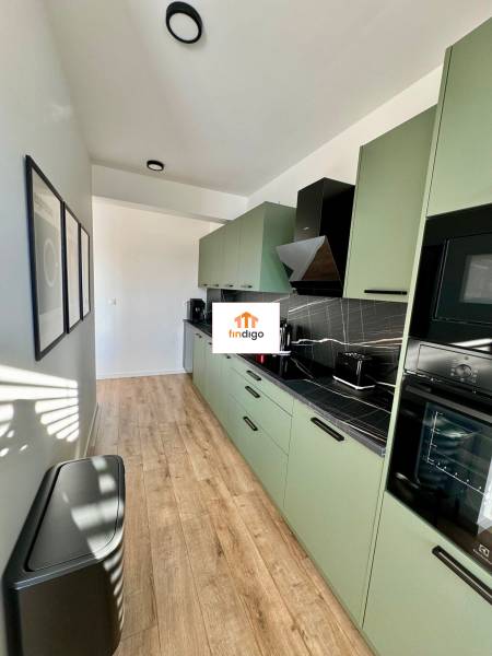 PREDAJ - 2-izbový byt v nádhernej lokalite Dvorníky - Kuchyňa v 2-izbovom byte s podlahou s dreveným dekorom a zelenými skrinkami.