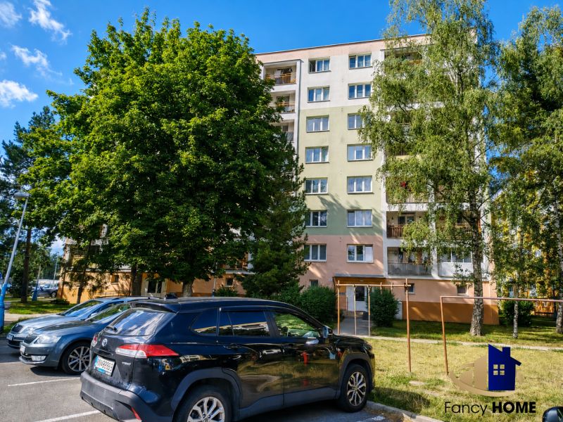 PRENÁJOM 2-izbový byt s loggiou ul. 29. augusta Poprad - Exteriér bytového domu na ulici 29. augusta v Poprade so zaparkovanými autami.