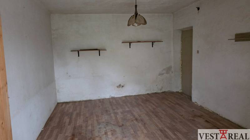 Na predaj 5 izbový rodinný dom Vinohrady nad Váhom - Izba v rodinnom dome s podlahou s dreveným dekorom a jednoduchým lustrom.