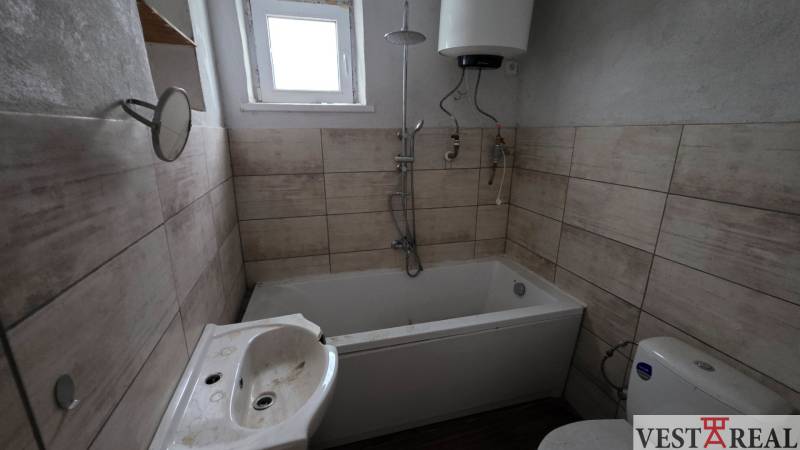 Na predaj 5 izbový rodinný dom Vinohrady nad Váhom - Kúpeľňa v rodinnom dome s vaňou, umývadlom a bojlerom, podlaha s dreveným dekorom.