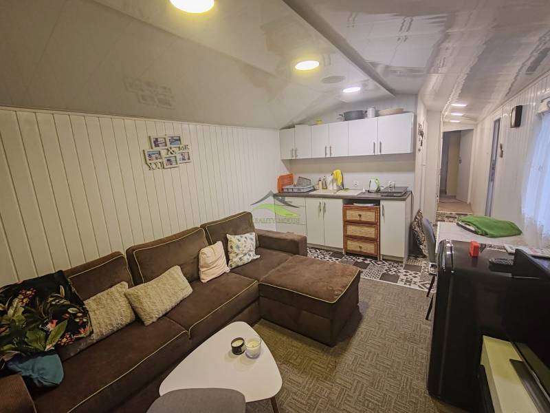 Pohoda pri vode, chata s výhľadom na Domašu - Obývacia izba v chate s pohodlnou sedačkou, kuchynskou linkou a dekoratívnym obkladom na stene.